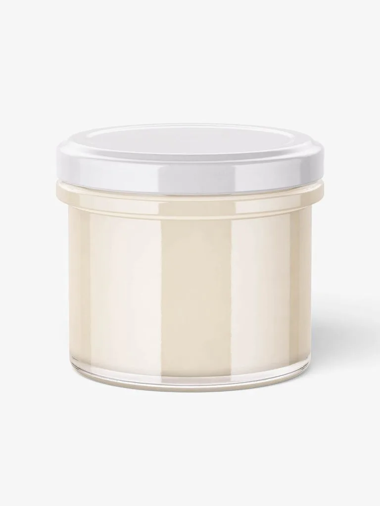 A low clear glass jar containing pale candle wax beneath a light lid.