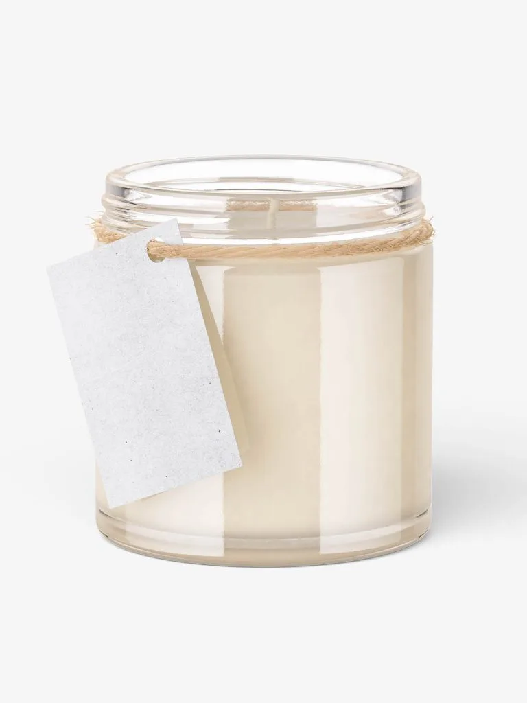 A tall clear jar containing pale candle wax, with a blank hanging paper tag.
