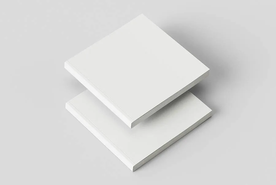 Two blank white square books stacked diagonally on a light gray background, viewed from above.