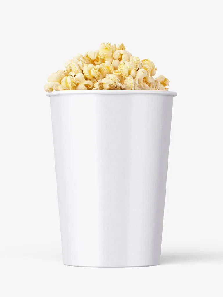 A tall tapered white paper bucket filled with popcorn above its rim.