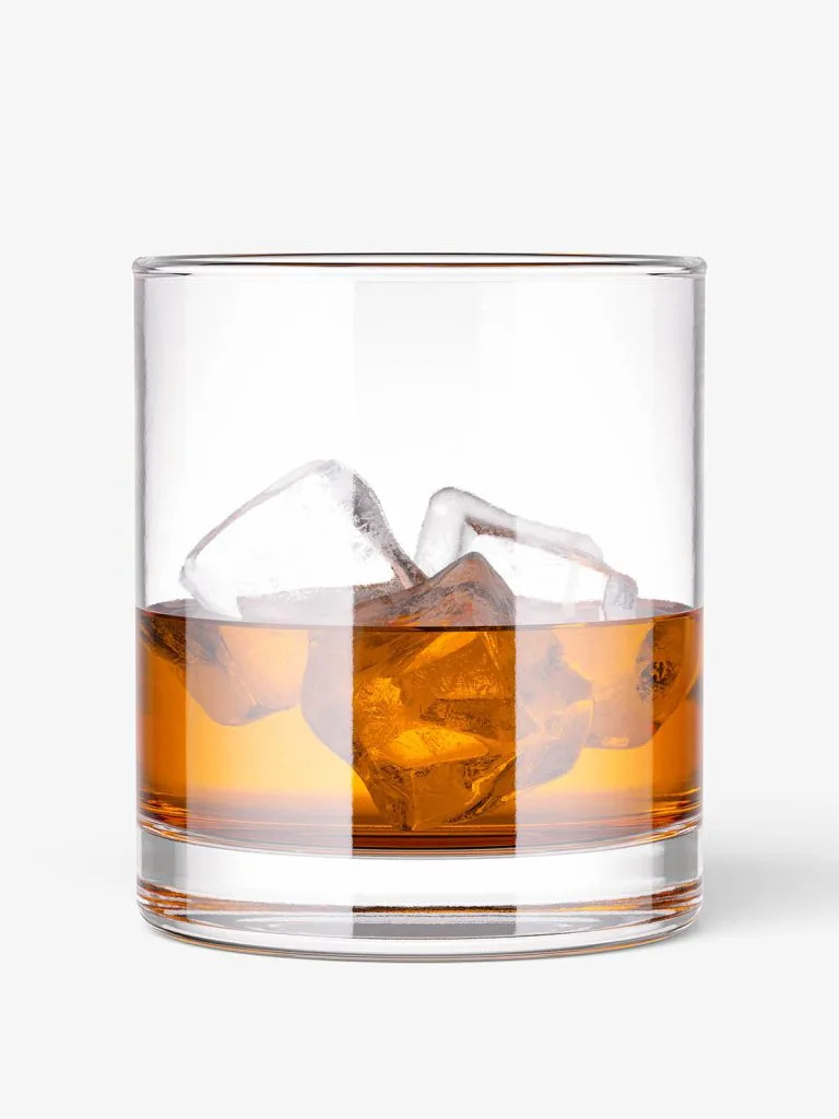 A clear rocks glass containing amber liquid and ice cubes.