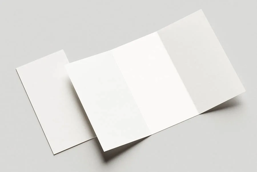 Unprinted white trifold flyer viewed from above at an angle on a light gray surface.