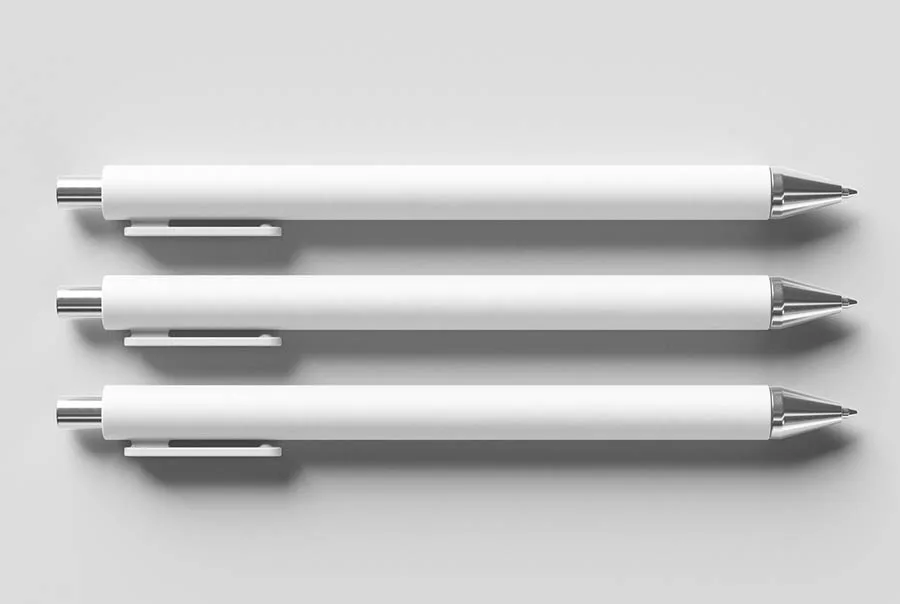 Three blank white ballpoint pens with silver clips and tips arranged horizontally on a light gray background.