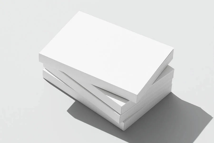 Three plain white paperback books in a loose stack, showing their covers, spines and page edges.